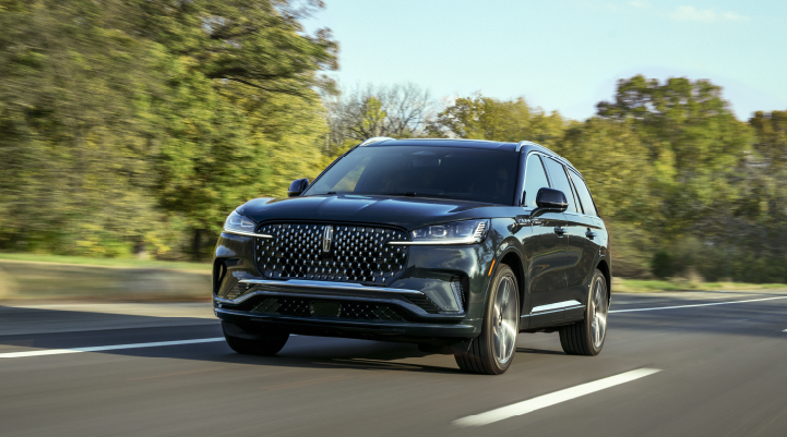 A 2025 Lincoln Black Label Aviator® SUV is being driven down a road lined with trees. | Capital Lincoln of Wilmington in Wilmington NC