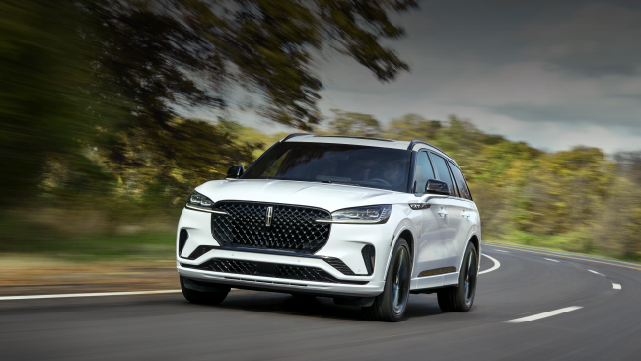 A white 2025 Lincoln Aviator® SUV is being driven down a road lined with trees. | Capital Lincoln of Wilmington in Wilmington NC