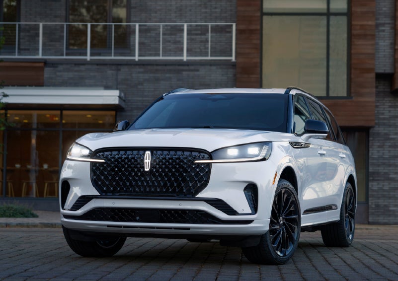 A 2026 Lincoln Aviator® Reserve model is shown with the available Jet Appearance Package parked near a restaurant. | Capital Lincoln of Wilmington in Wilmington NC