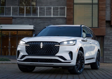 A 2026 Lincoln Aviator® Reserve model is shown with the available Jet Appearance Package parked near a restaurant. | Capital Lincoln of Wilmington in Wilmington NC