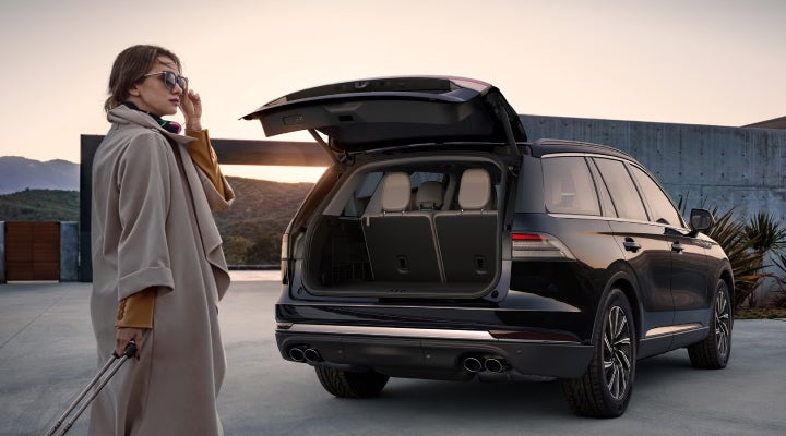 A woman approaches a 2026 Lincoln Aviator® SUV with its rear liftgate open. | Capital Lincoln of Wilmington in Wilmington NC