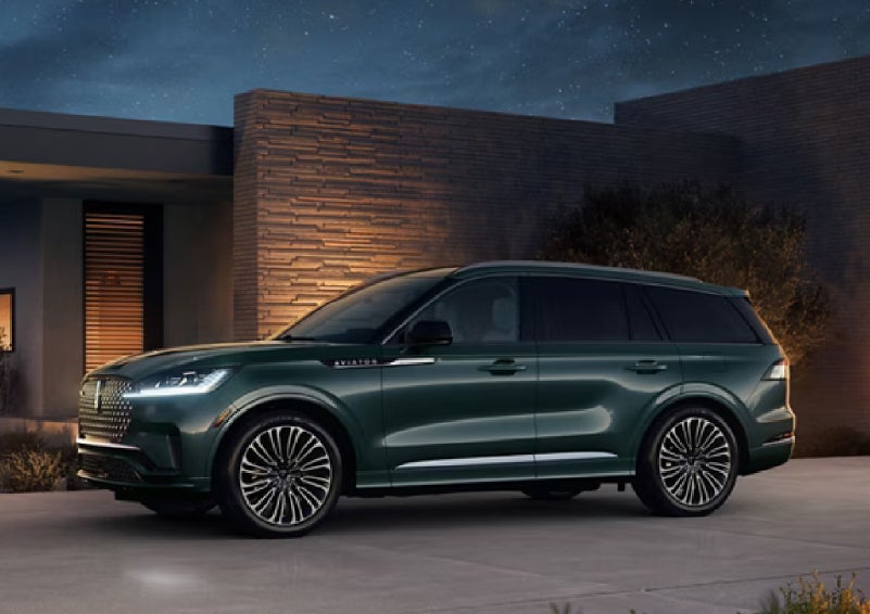 A green 2027 Lincoln Aviator® SUV is parked outside a contemporary home. | Capital Lincoln of Wilmington in Wilmington NC