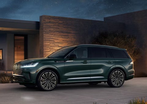 A green 2027 Lincoln Aviator® SUV is parked outside a contemporary home. | Capital Lincoln of Wilmington in Wilmington NC