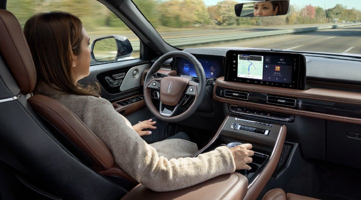 A 2027 Lincoln Aviator® SUV is being driven hands-free on a highway lined with trees. | Capital Lincoln of Wilmington in Wilmington NC