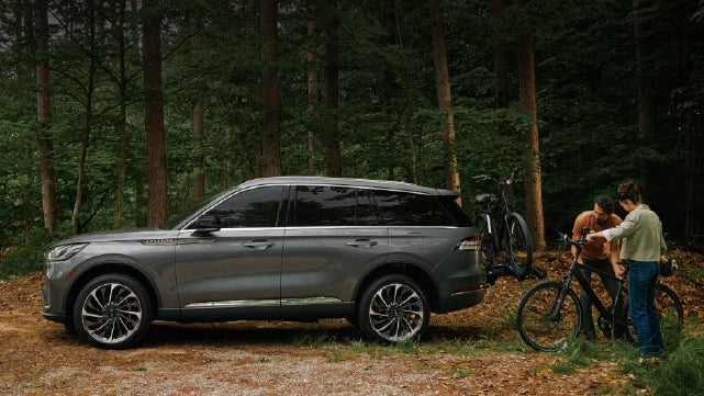 A father and son load e-bikes on a bike rack attached to a 2027 Lincoln Aviator® SUV. | Capital Lincoln of Wilmington in Wilmington NC