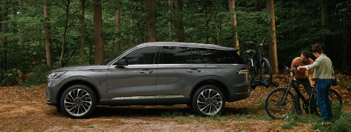 A father and son load e-bikes on a bike rack attached to a 2027 Lincoln Aviator® SUV. | Capital Lincoln of Wilmington in Wilmington NC