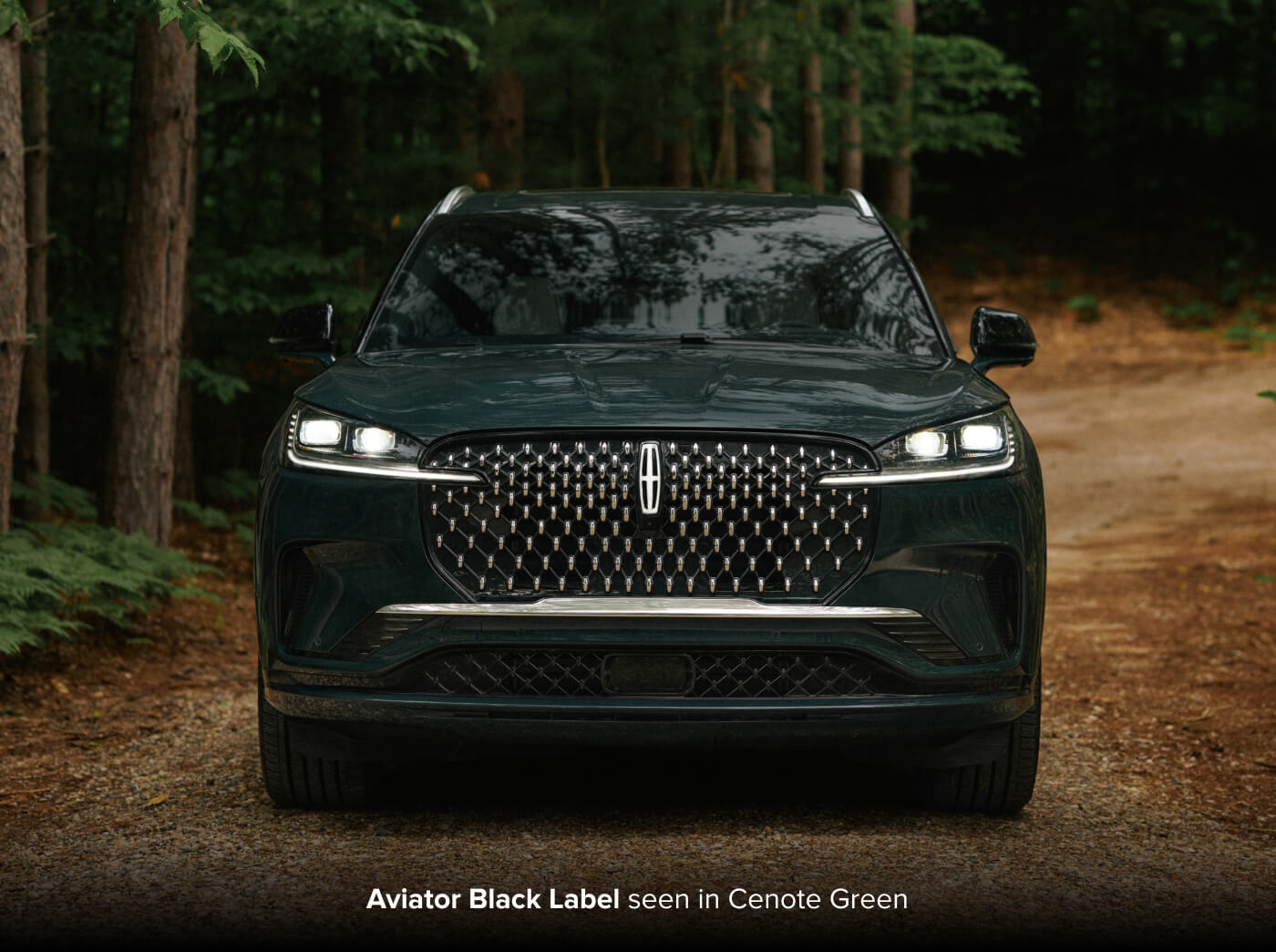 2027 Lincoln Aviator Black Label in Cenote Green, front view parked on a wooded trail.