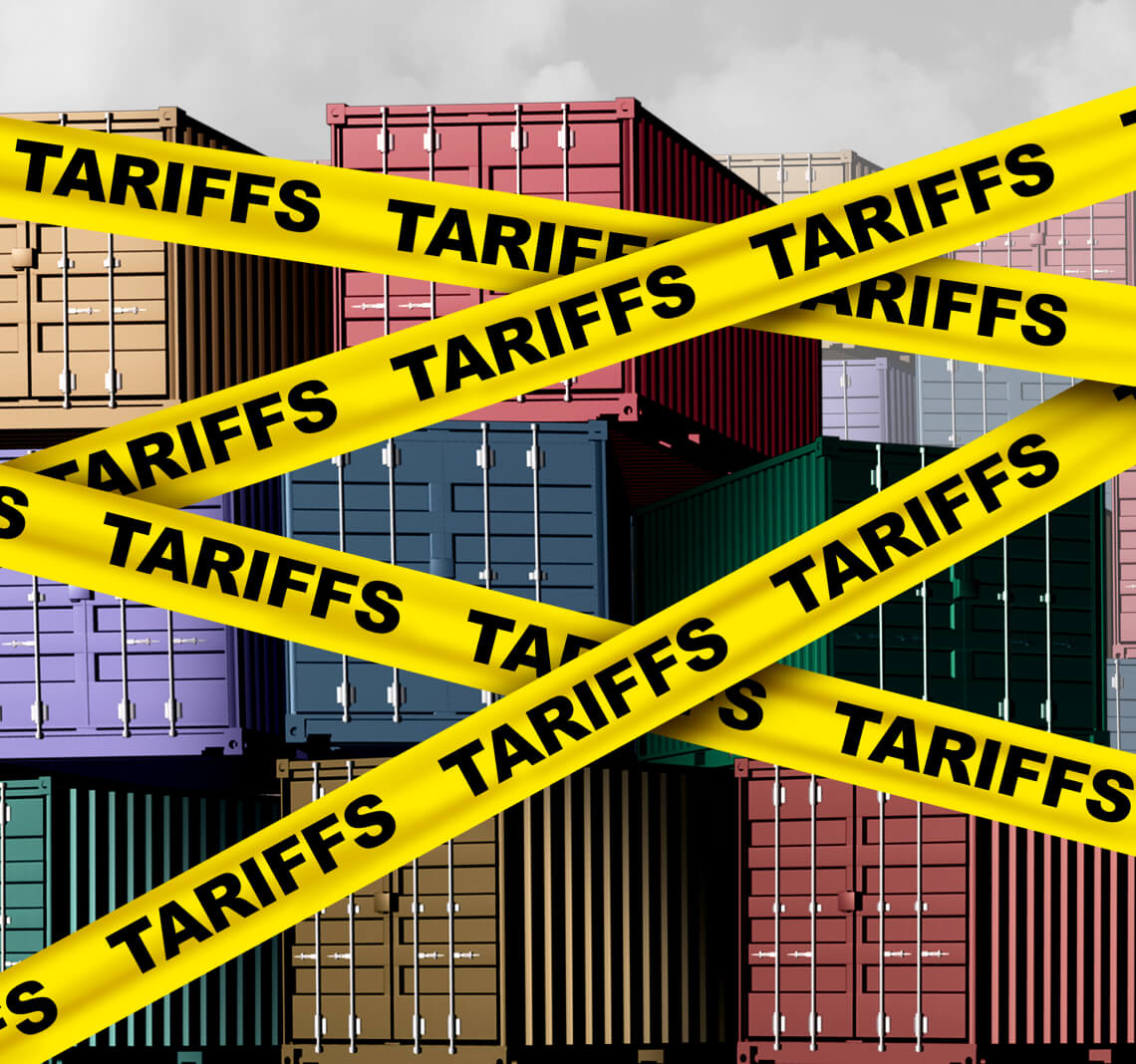 Stacks of shipping crates wrapped in yellow tape with the word Tariffs on it.