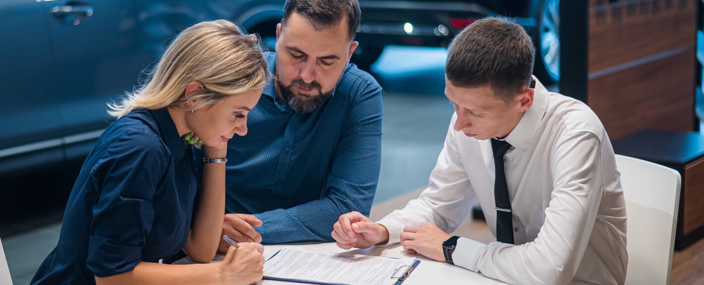 Customers signing paperwork with a Lincoln Sales Associate