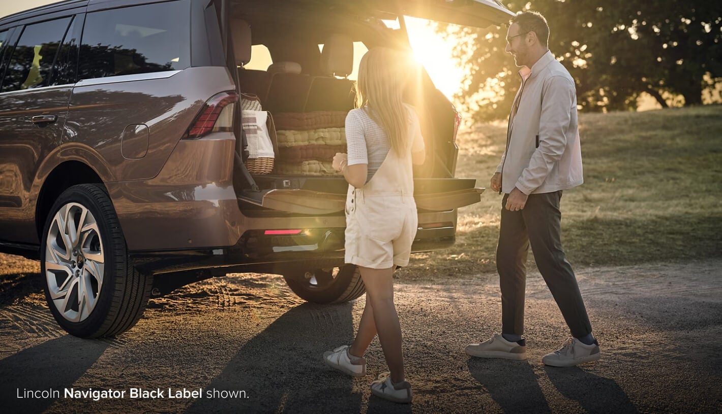 Couple loading trunk of Lincoln Navigator Black Label
